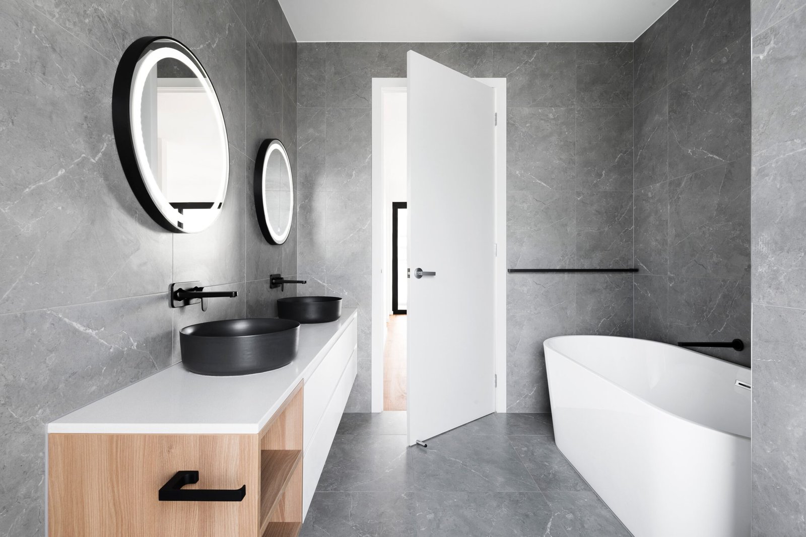 image showing a grey tiled bathroom with white and black furniture